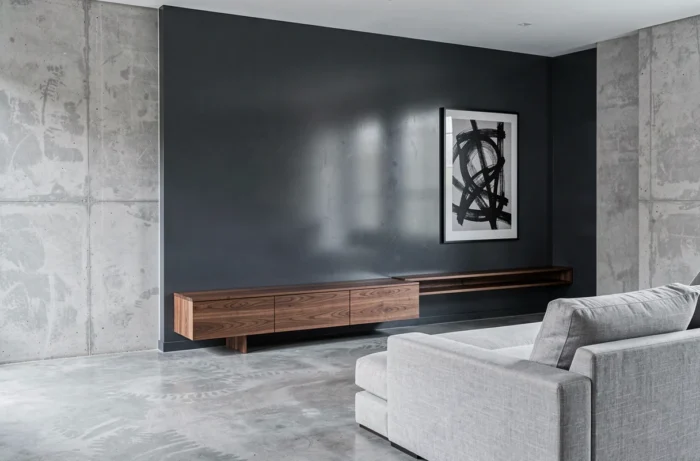 Mur en gris anthracite laque satinée dans un salon minimaliste avec crédence en noyer et sol en microciment