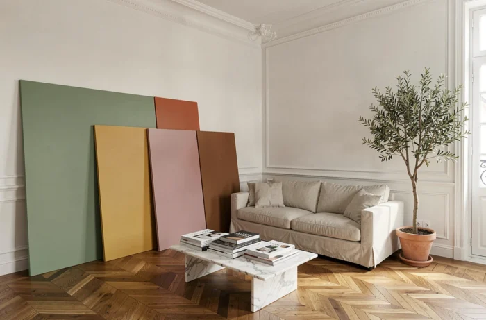Salon moderne avec plusieurs échantillons de peintures tendance aux couleurs variées appuyés contre un mur blanc