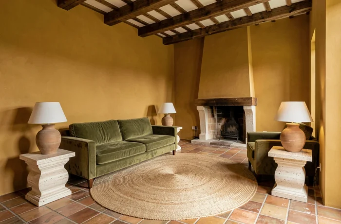 Salon avec murs en ocre doré finition mate, canapé en velours olive et carrelage en terre cuite