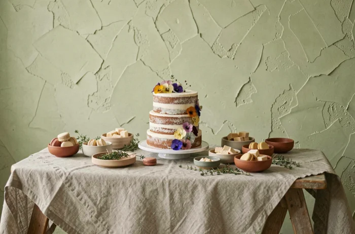 Table de desserts de mariage minimaliste avec gâteau naked cake, macarons et décor végétal en tons sauge et terracotta